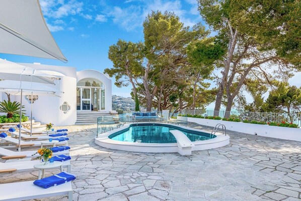 A pool area with lounge chairs, a pool, and a building with a view. - Villa Vento Blu, Exclusive Luxury in Capri (Anacapri)