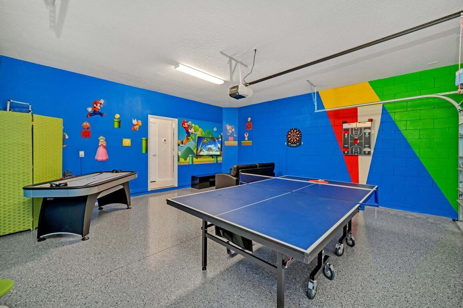 Una stanza con tavolo da ping pong, freccette e schermo televisivo.