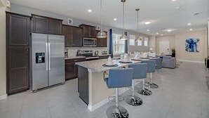Een moderne keuken met donkerhouten kastjes, roestvrijstalen apparatuur en een centraal kookeiland met barstoelen.