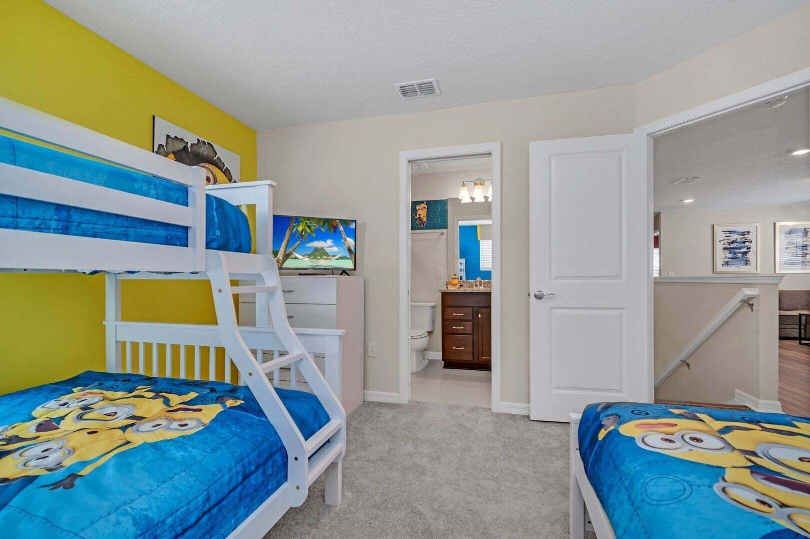 A child's bedroom with bunk beds, a TV, and a bathroom visible through an open door.