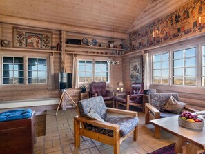 Ein Holzinterieur mit Kamin, Ledersesseln, einem Fernseher und Kunstwerken an den Wänden.