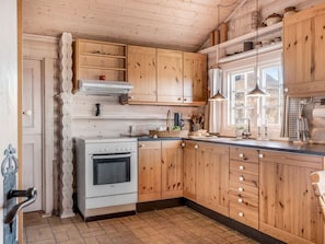 Eine Küche mit Holzausstattung, einem weißen Bosch-Ofen und einem Fenster mit Blick.