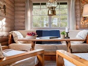 A cozy cabin interior with a wooden bench, a table with a book and a bowl of fruit, and a window with a view of the outdoors. - "Apelone" - 450m from the sea by Interhome (Blokhus)