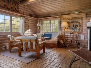 A cozy log cabin interior with a sofa, wooden chairs, a table, and a lamp. - "Apelone" - 450m from the sea by Interhome (Blokhus)