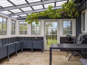 A covered patio with a wooden deck, built-in benches, a table, and a grill area. - "Elodie" - 10m from the sea by Interhome (Bjert)