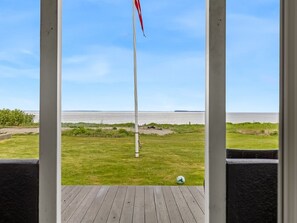 A flagpole in a grassy area with a view of a body of water and distant land. - "Elodie" - 10m from the sea by Interhome (Bjert)