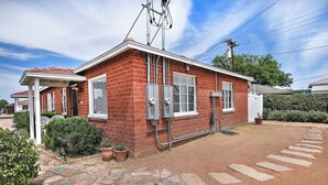 Een huis met één verdieping, gebouwd van baksteen, met een overdekte veranda, een pad van stenen en een kleine tuin.