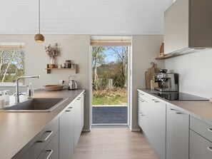 Een moderne keuken met een groot schiereiland, ingebouwde apparatuur en uitzicht op het buitengebied.