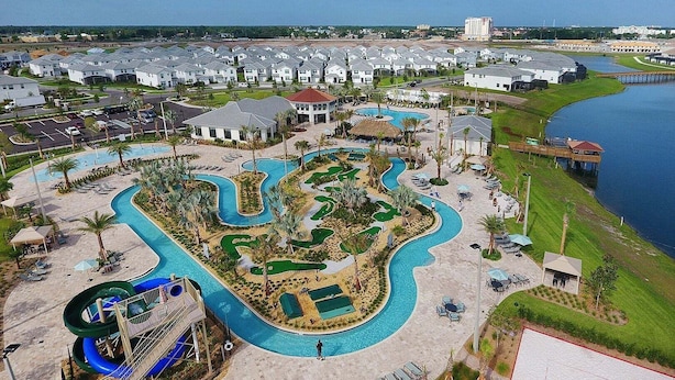 An aerial view of a resort with a central pool area, a water slide, and a marina. - Fancy Family Home 10min-disney Private Pool 108 (Kissimmee)