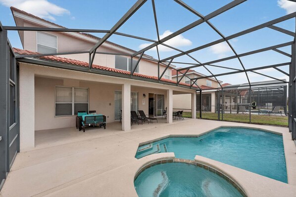 A covered outdoor swimming pool with a patio area, chairs, and a table. - Family Getaway: 6BR w/ Private Pool & Resort Access (Davenport)