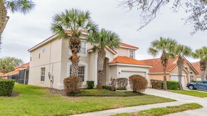 A two-story house with a red-tiled roof, palm trees, and a well-maintained lawn. - Family Getaway: 6BR w/ Private Pool & Resort Access (Davenport)