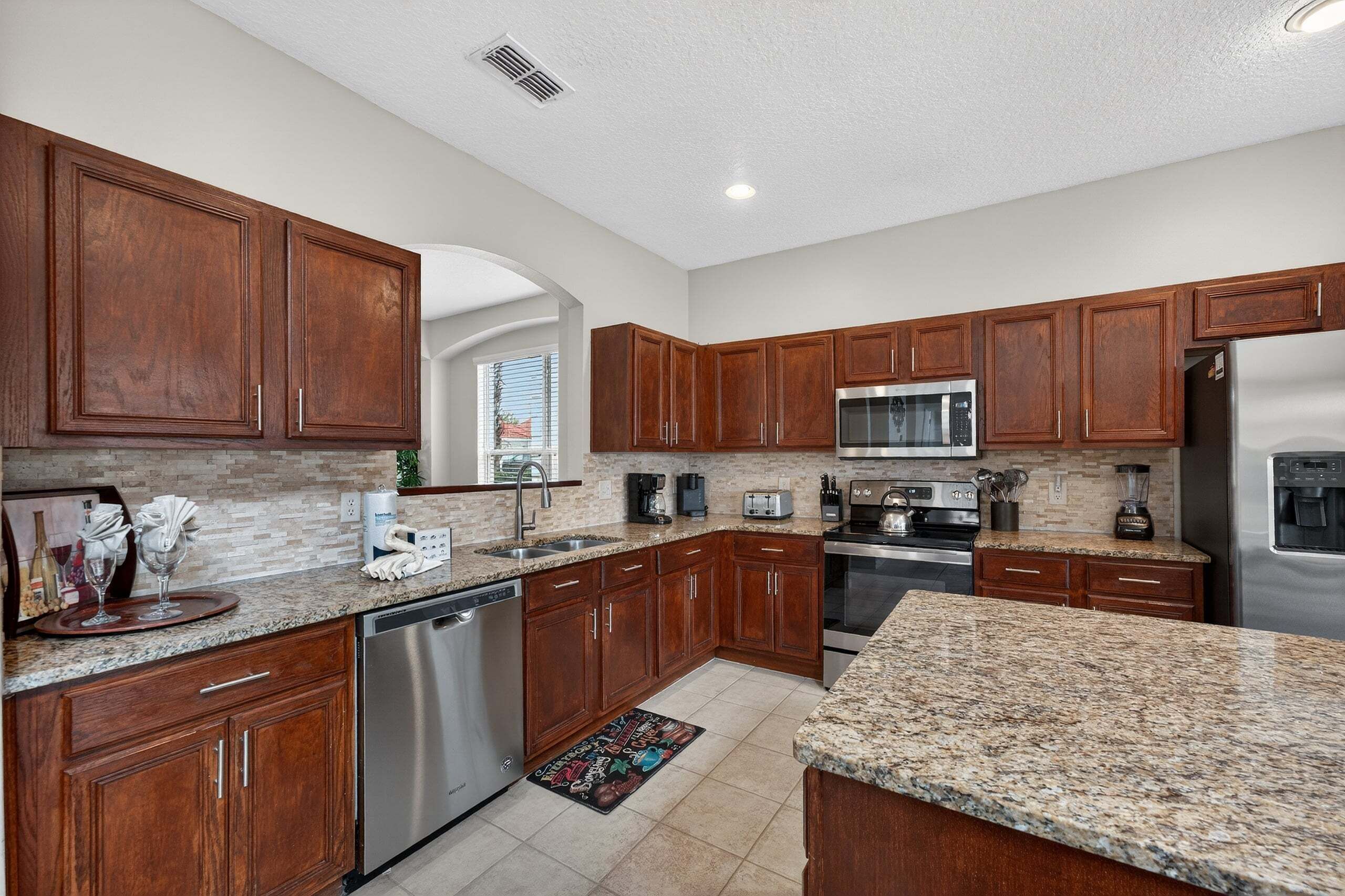 A modern kitchen with granite countertops, stainless steel appliances, and wooden cabinets.
