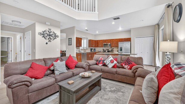 A spacious living area with a brown sofa set, a wooden coffee table, and a kitchen in the background. - Family Getaway: 6BR w/ Private Pool & Resort Access (Davenport)