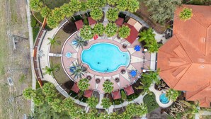 An aerial view of a resort with a central swimming pool, surrounded by palm trees and outdoor seating areas. - Family Getaway: 6BR w/ Private Pool & Resort Access (Davenport)