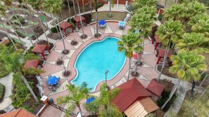 A pool area with a central swimming pool, surrounding palm trees, and red-roofed structures. - Family Getaway: 6BR w/ Private Pool & Resort Access (Davenport)