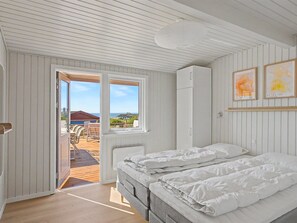 Ein Schlafzimmer mit Bett, Kleiderschrank und Blick ins Freie.