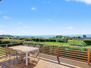 A wooden deck with a table and chairs, overlooking a landscaped garden and a body of water. - "Teofan" - 325m from the sea by Interhome (Ebberup)