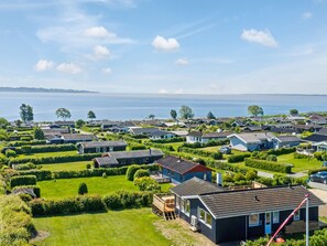Ein Küstenwohngebiet mit Häusern, grünen Rasenflächen und Blick auf das Meer.
