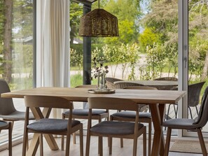 A dining area with a wooden table, grey upholstered chairs, a wicker pendant light, and a vase with flowers. - "Ingalil" - 825m from the sea by Interhome (Kalundborg)
