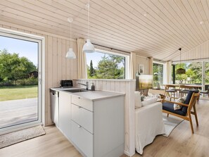 Una cocina moderna con una isla integrada, ventanas amplias y un comedor con vistas al exterior.