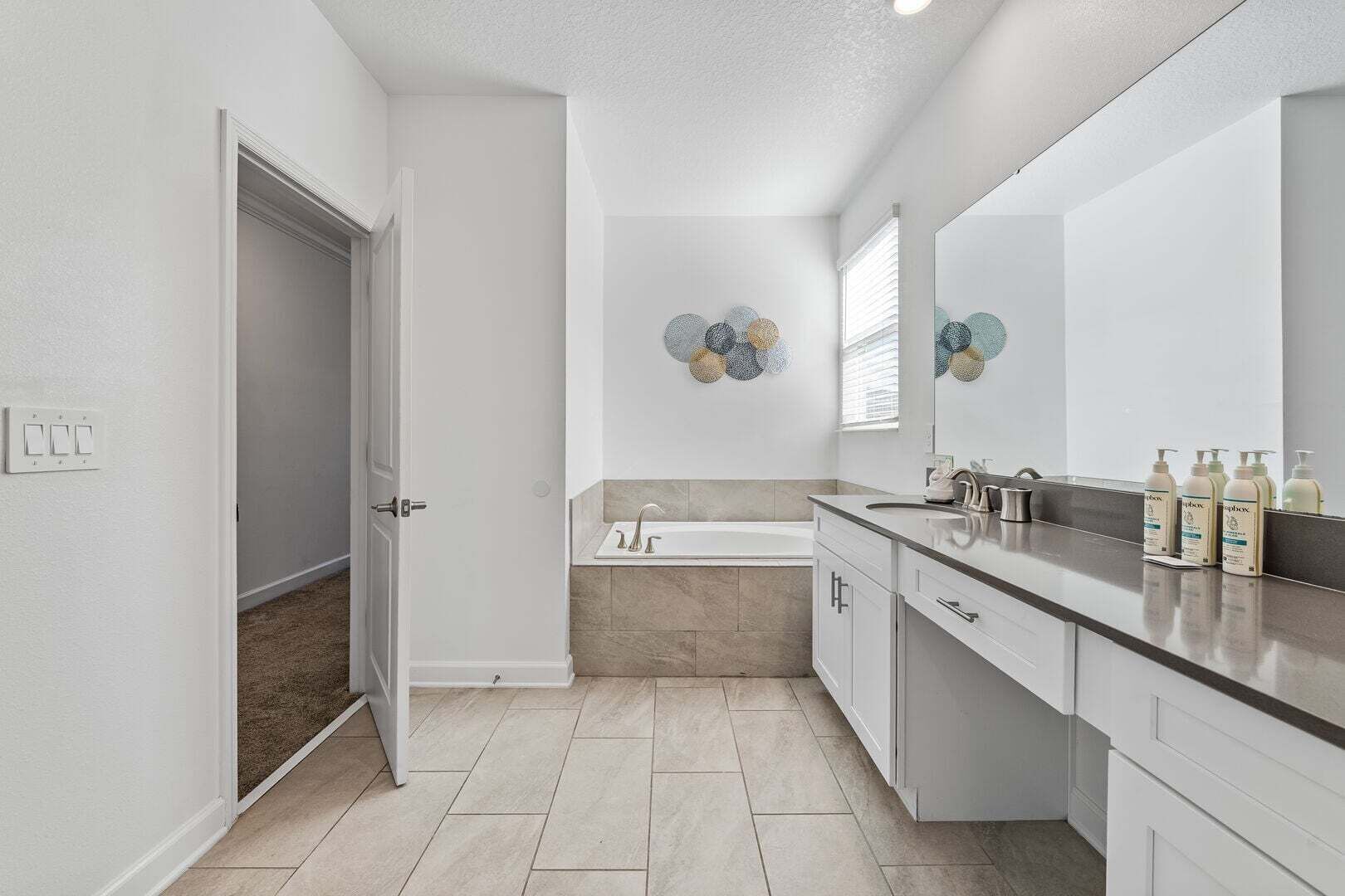 Un bagno moderno con una vasca, uno specchio grande e un mobile lavabo con articoli da toilette.
