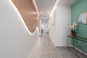 Ein moderner Flur mit einer gewölbten Holzverkleidung, einem Glastischchen mit Pflanze und einer Wand in Türkis.