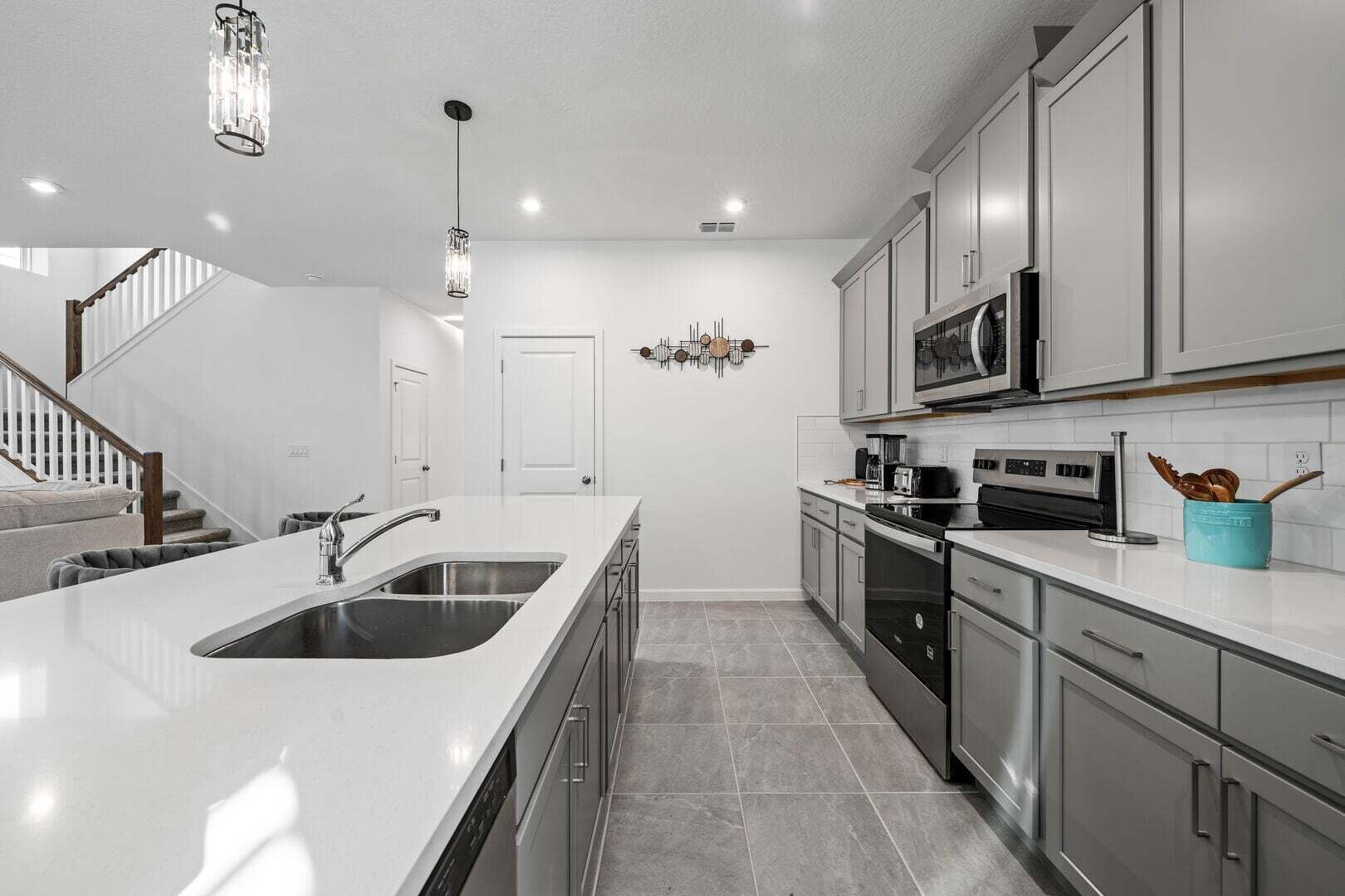 Una cocina moderna con una isla central, electrodomésticos de acero inoxidable y una escalera que sube a otro nivel.