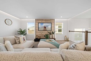 Ein Wohnzimmer mit großem Fernseher, zwei Sofas, einem Couchtisch und einer Wand mit Holzpaneelen.