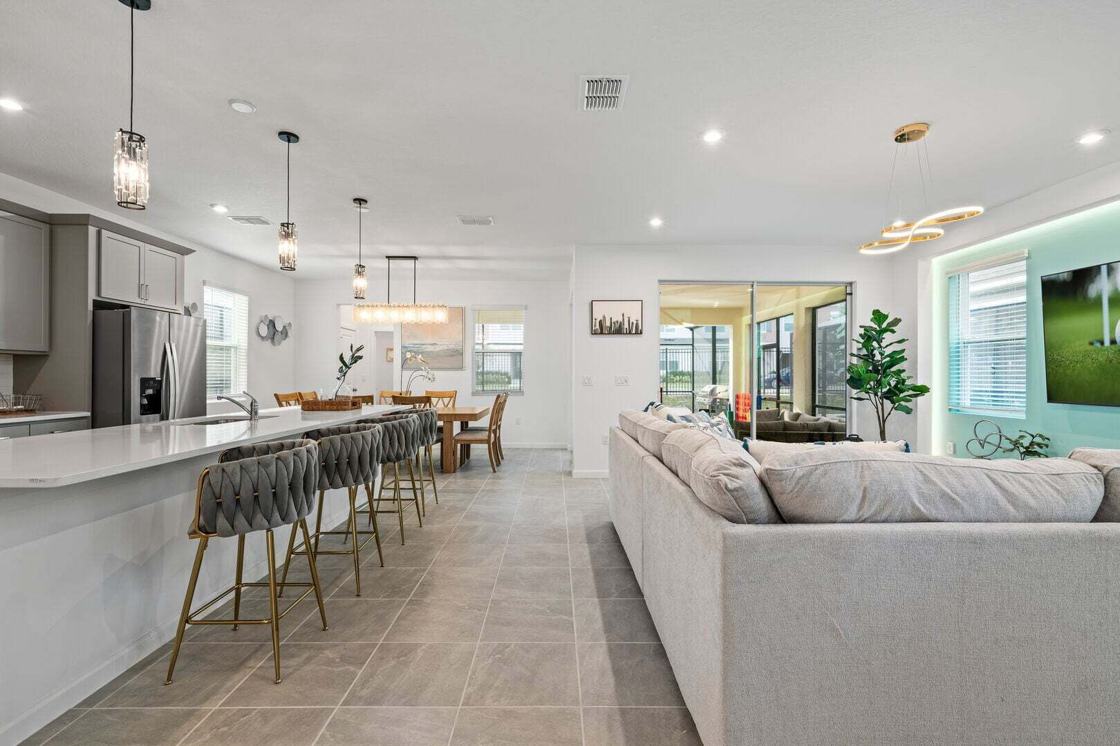 Una cocina moderna con una isla central, comedor con sillas y sala de estar con un sofá.