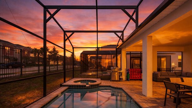 Una piscina con hidromasaje, mobiliario exterior y un patio cubierto.