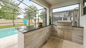 Eine moderne Außenküche mit Pool, großen Fenstern und Grill.