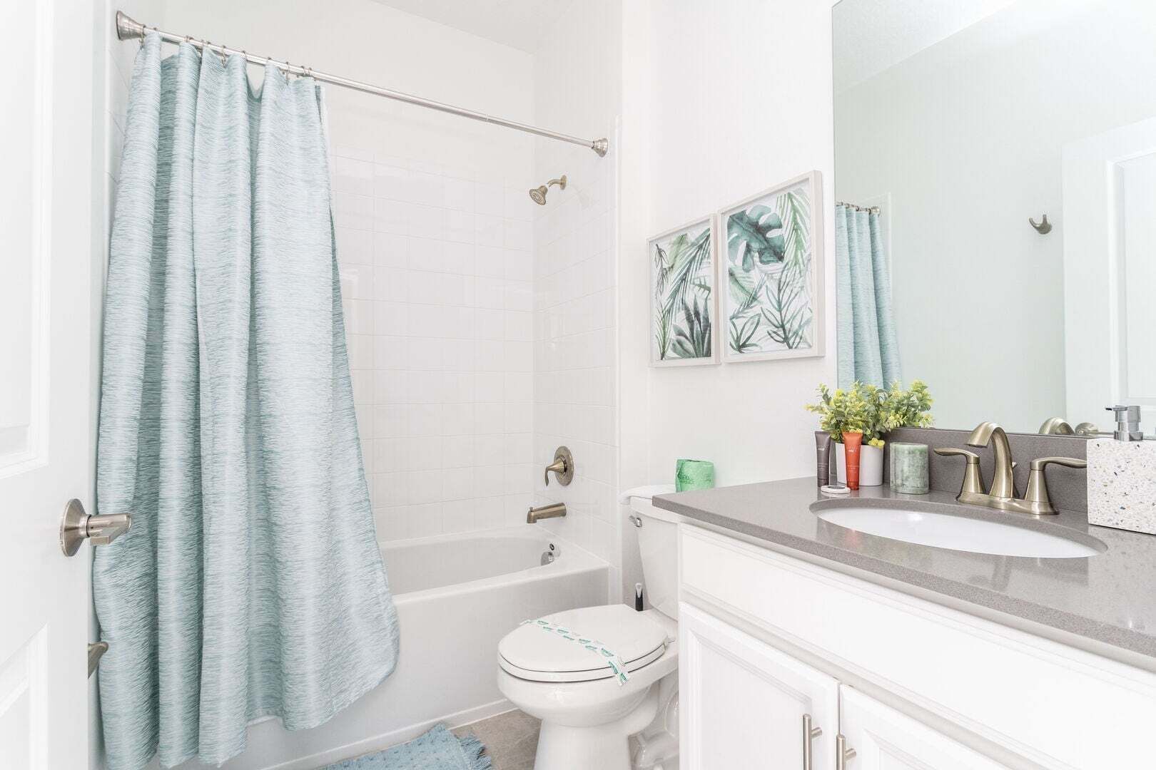 A bathroom with a bathtub, toilet, sink, and a shower curtain.