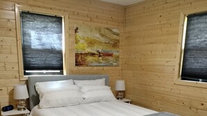 Une chambre aux murs lambrissés, avec un lit, des lampes de chevet et un tableau accroché au mur.