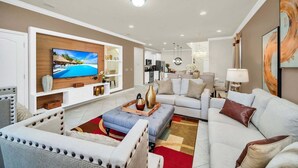 Een moderne woonkamer met een flatscreen televisie, banken, een salontafel en een eethoek.