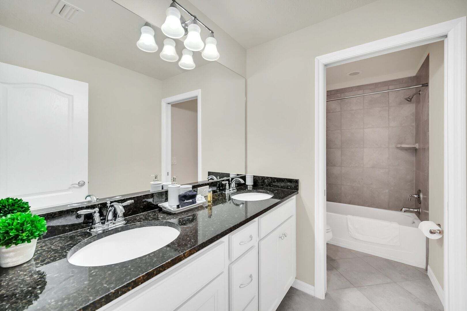 A modern bathroom with two sinks, a large mirror, and a shower area.