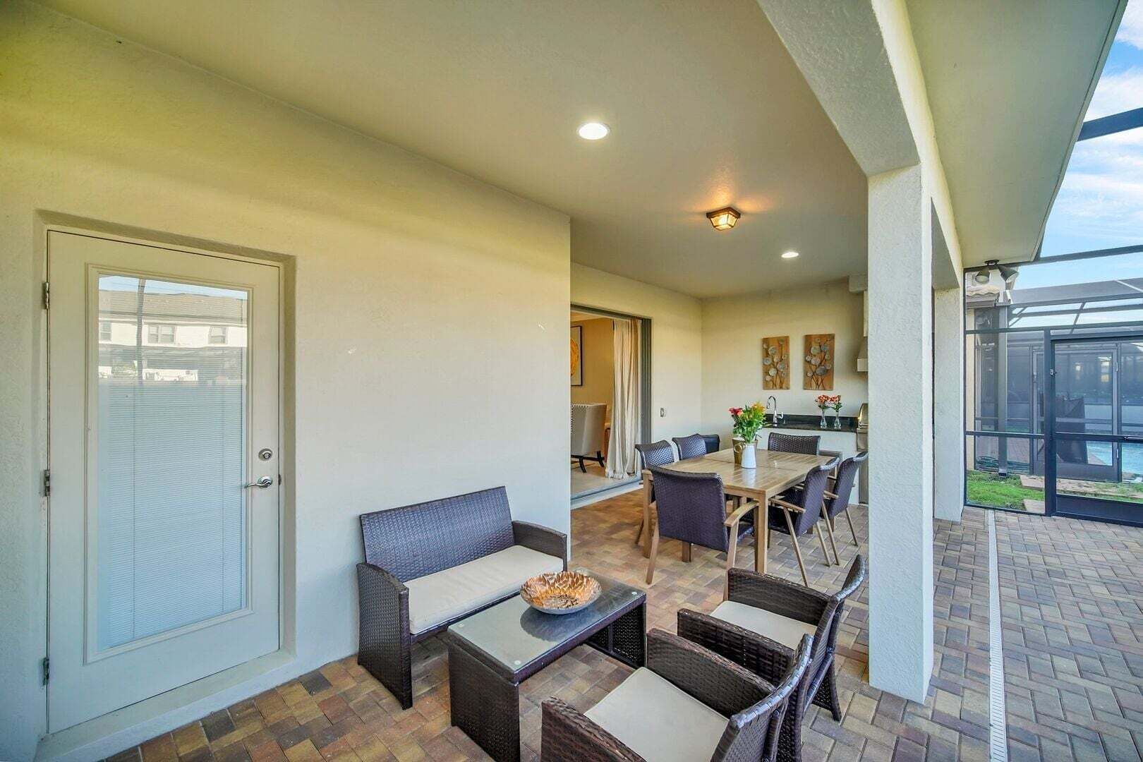 A covered patio with a dining area, a sofa, and a fire feature.