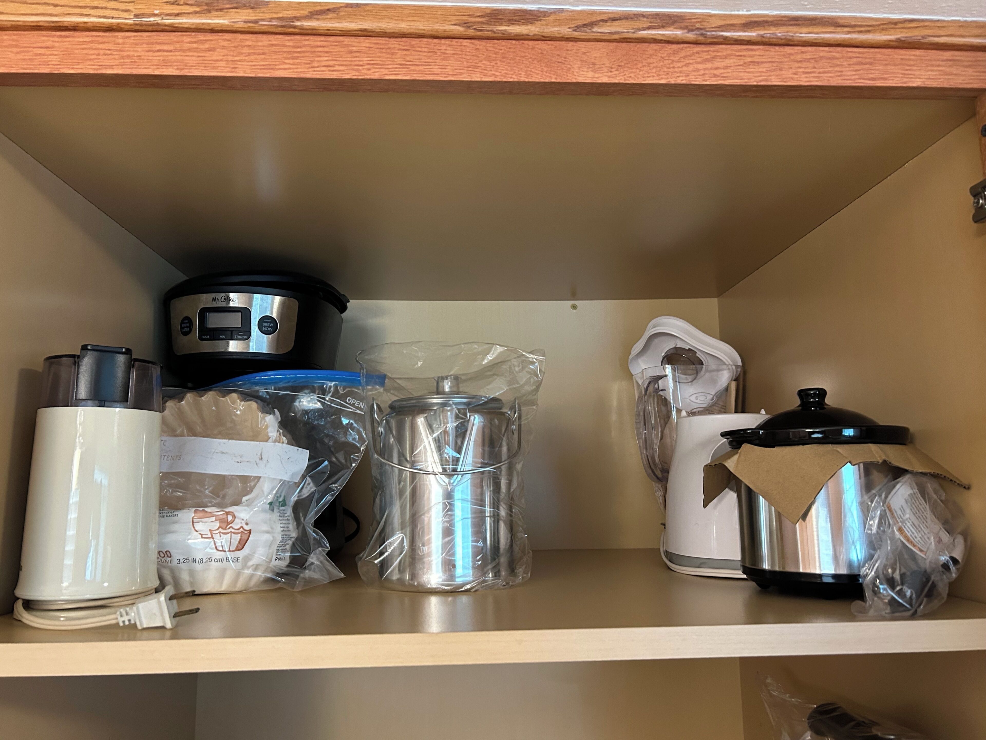 Estant de cuina amb una cafetera, una cocedora d'arròs, una bullidora i una olla, tot plegat dins les seves envasos.