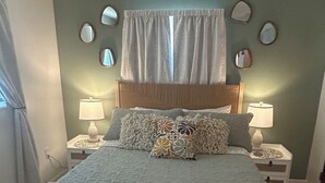 A bedroom with a bed, two bedside tables with lamps, a ceiling fan, a window with curtains, and wall-mounted mirrors. - Waterfront Canal/Park Your Boat (Homosassa)