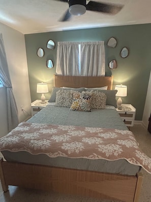 A bedroom with a bed, two bedside tables with lamps, a ceiling fan, a window with curtains, and wall-mounted mirrors. - Waterfront Canal/Park Your Boat (Homosassa)