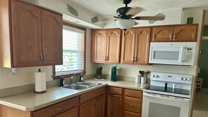 A kitchen with wooden cabinets, a sink, a microwave, and an oven. - Waterfront Canal/Park Your Boat (Homosassa)