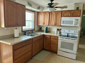 A kitchen with wooden cabinets, a sink, a microwave, and an oven. - Waterfront Canal/Park Your Boat (Homosassa)