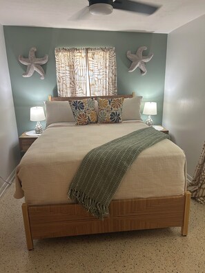 A bed with a wooden frame, two bedside tables with lamps, and decorative wall art. - Waterfront Canal/Park Your Boat (Homosassa)