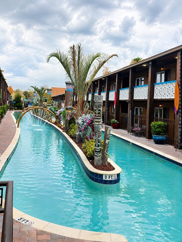 A swimming pool with a 3 ft depth marker, surrounded by tropical plants and tiki statues.