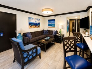 A living room with a sofa, coffee table, and chairs, a dining area with a table and chairs, and artwork on the walls.