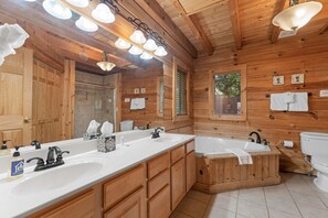 A wooden cabin-style bathroom with two sinks, a bathtub, and a large mirror.