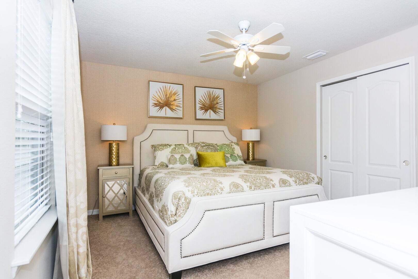 A bedroom with a bed, bedside tables, a ceiling fan, and a door.