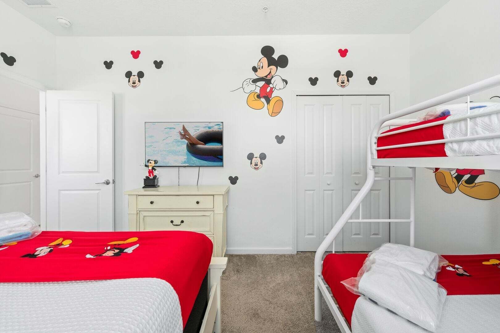 A child's room with bunk beds, a dresser, and Mickey Mouse decals.