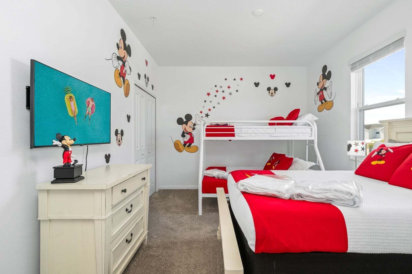 Una habitación infantil con literas, un aparador, un escritorio y adornos en la pared.