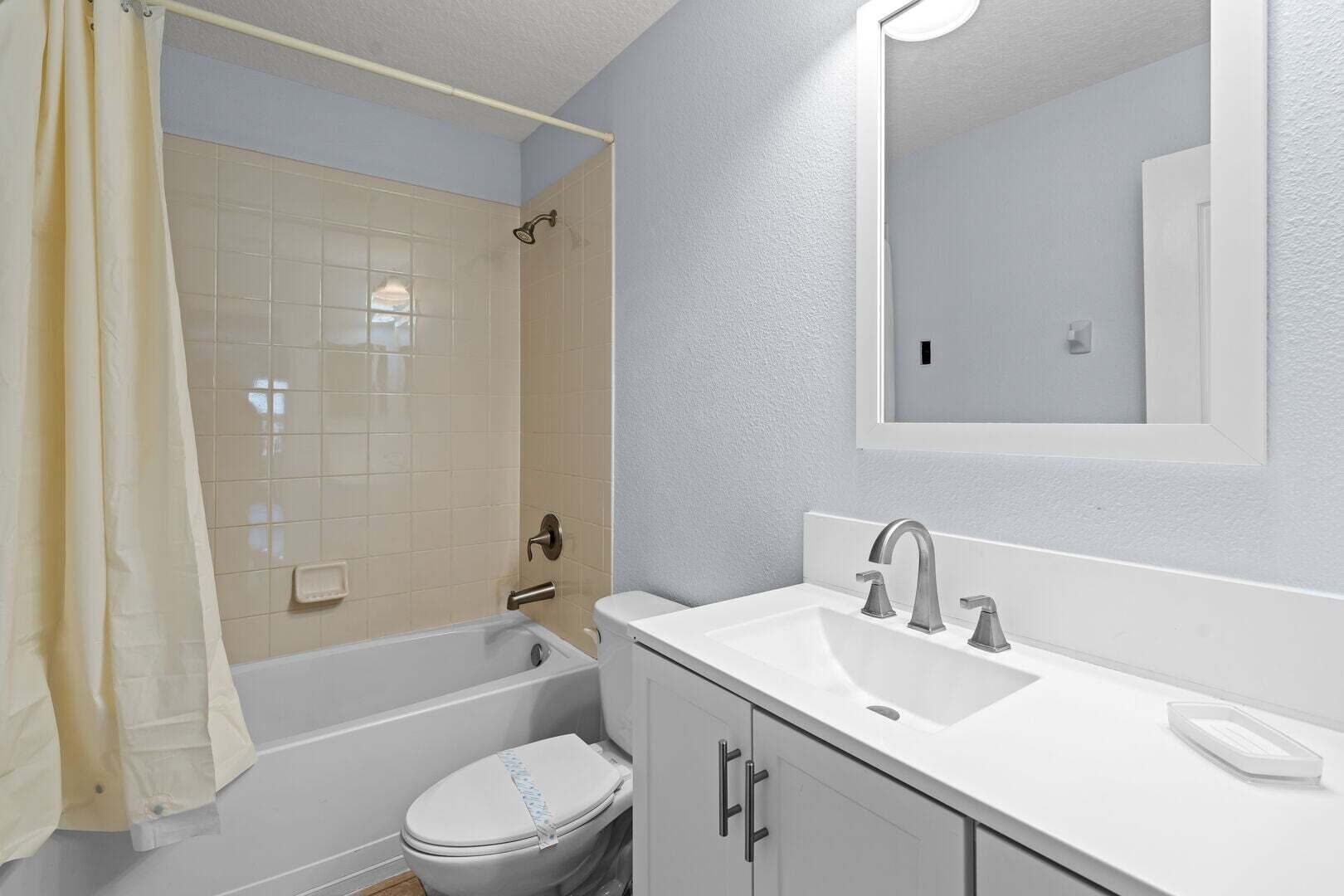 A bathroom with a bathtub, toilet, sink, and mirror.