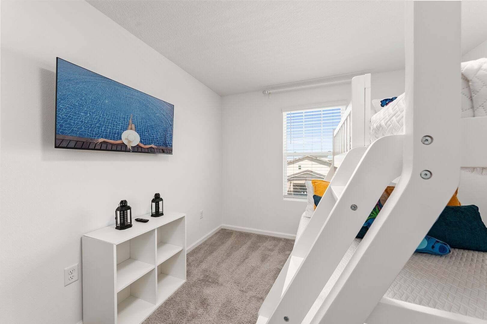 Ein Kinderzimmer mit Etagenbett, einem Bild von einem Schwimmbad, einer weißen Ablagetisch und einem Fenster mit Blick auf Gebäude.